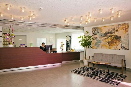 a woman sitting at a reception desk in a lobby at Séjours & Affaires Massy Atlantis in Massy