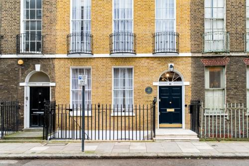 a brick building with two doors and a fence at GuestReady - The Fitzroy Hotel in London