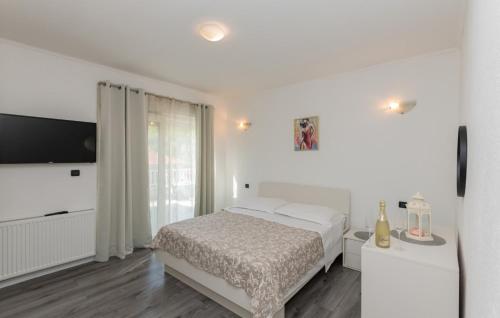 Un dormitorio blanco con una cama y un televisor de pantalla plana. en Villa FourM - Makarska by Villas Guide, en Poljica