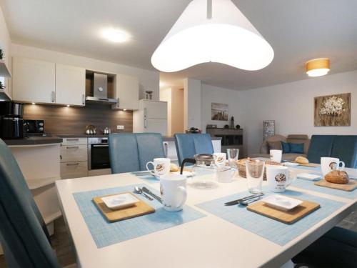 a white table with blue chairs and a kitchen at Schatzkiste Reetdachhaus in Tarnewitz