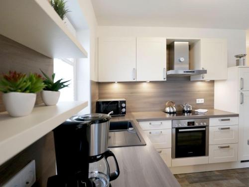 a kitchen with white cabinets and a coffee maker at Schatzkiste Reetdachhaus in Tarnewitz
