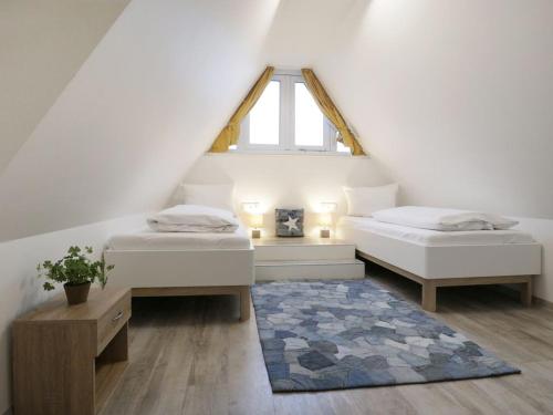 a attic bedroom with two beds and a window at Schatzkiste Reetdachhaus in Tarnewitz