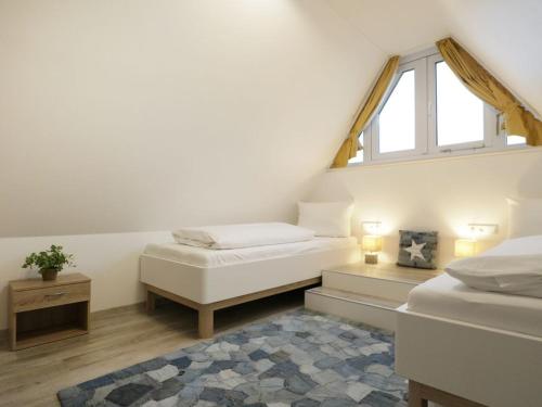 a attic room with two beds and a window at Schatzkiste Reetdachhaus in Tarnewitz