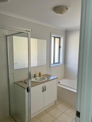 a white bathroom with a sink and a bath tub at Secure 4BR Garage Whyalla in Whyalla Airport