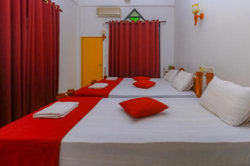 two beds in a room with red curtains at Castle Resort Yala in Tissamaharama