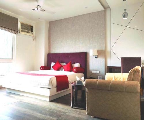 a bedroom with a bed with red pillows and a couch at Hotel Gurveer Royal in Lucknow