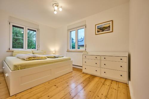 a bedroom with a bed with a dresser and two windows at Idyllische Ruhe Der Villa Hedwig in Kurort Gohrisch