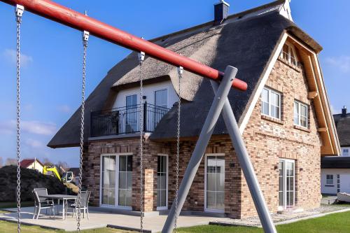 a house with a thatched roof with a swing at Reethaus Nordlicht A Top-class in Dranske