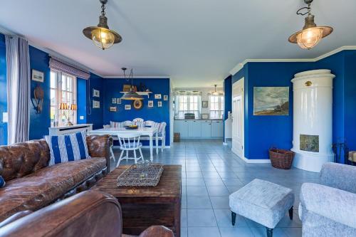 sala de estar con paredes azules, sofá y mesa en Haus Lotte, en Utersum