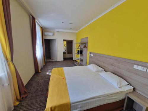 a bedroom with a large bed with a yellow wall at Optima Vinnytsia in Vinnytsya