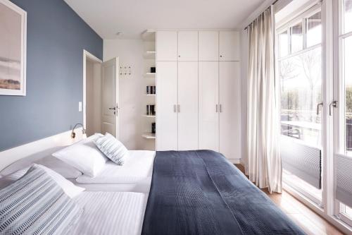 a bedroom with a white bed and a large window at Haus Leuchtfeuer 1 in Wyk auf Föhr