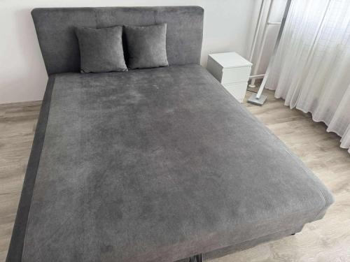 a large bed with a grey blanket on top of it at MiDo in Zalaegerszeg