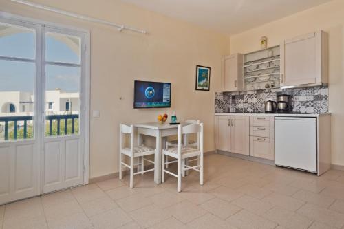 a kitchen with a table and chairs and a refrigerator at Popi Studios in Arkasa