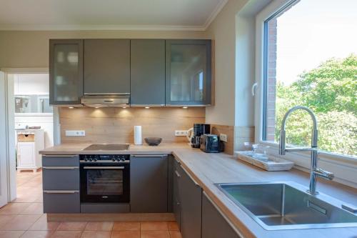 a kitchen with stainless steel appliances and a large window at Haus am Strand in Wyk auf Föhr
