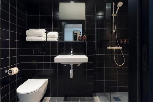 a black tiled bathroom with a toilet and a sink at The Social Hub Florence Lavagnini Extended Stay in Florence