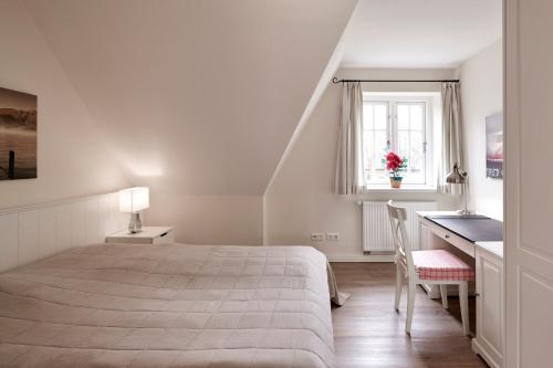 a bedroom with a bed and a desk and a window at Hüs Godewind in Alkersum