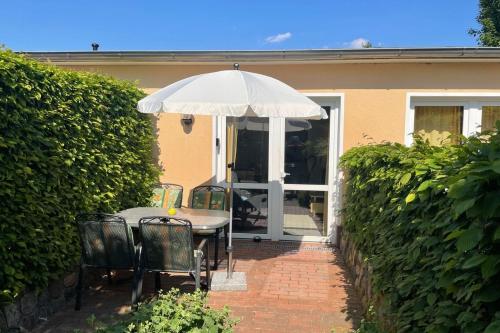 a table and chairs with an umbrella in front of a house at UG-Buche in Göhren-Lebbin