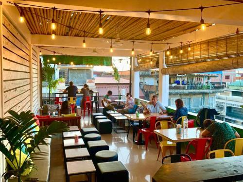 a group of people sitting at tables in a restaurant at THE PLACE Hostel Battambang in Battambang