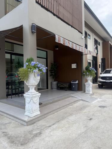 two vases with flowers in them outside of a building at Cha V Place Buriram - ชาวีเพลส บุรีรัมย์ in Ban Yang