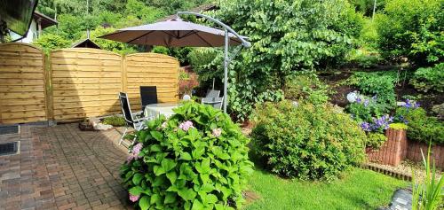 a garden with an umbrella and a table and chairs at Ferienhaus Korn mitten im schönen Pfälzer Wald, Privat Haus in Bruchweiler-Bärenbach