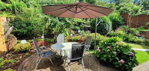 a table and chairs with an umbrella in a garden at Ferienhaus Korn mitten im schönen Pfälzer Wald, Privat Haus in Bruchweiler-Bärenbach