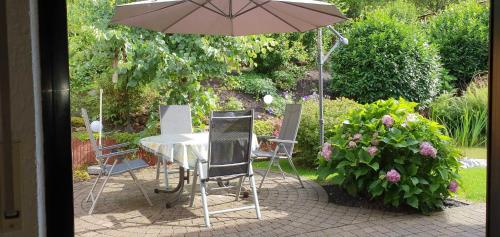 a table and chairs with an umbrella in a garden at Ferienhaus Korn mitten im schönen Pfälzer Wald, Privat Haus in Bruchweiler-Bärenbach