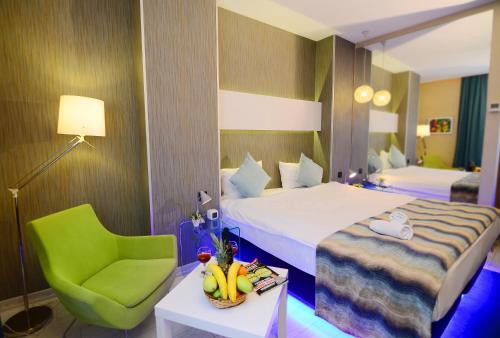 イスタンブールにあるTempo Hotel 4Leventのベッドと緑の椅子が備わるホテルルームです。