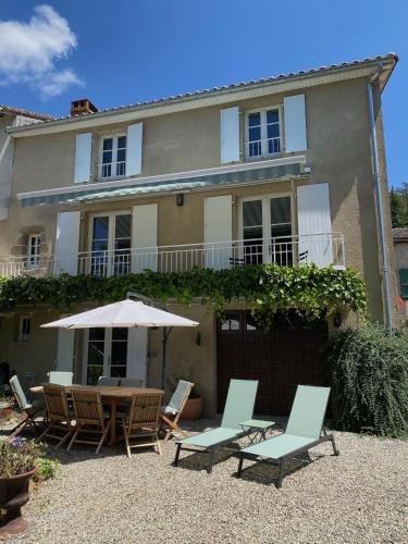 a house with chairs and a table and an umbrella at Le Caprice garden, river and chateau in Saint-Germain-de-Confolens