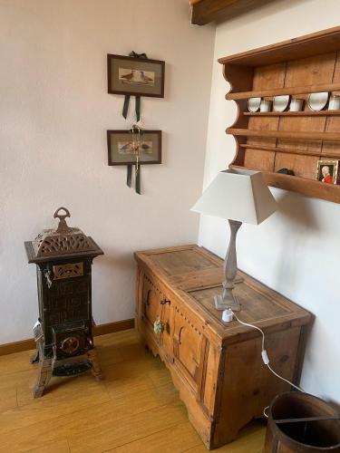 a room with a table with a lamp on a chest at Casa Serena in Cavalese