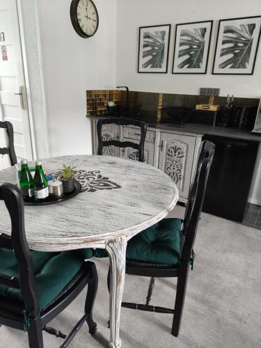 a dining room table with chairs and a clock on the wall at Oaza Spokoju in Szczawno-Zdrój