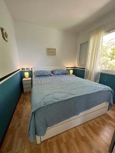 a bedroom with a bed with a blue comforter and a window at House Neli in Srednje Selo na Šolti
