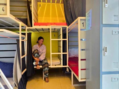 a person sitting in a room with bunk beds at THE PLACE Hostel Battambang in Battambang
