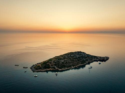 an island in the middle of the water at sunset at Alýria Sea Side Suites in Agios Nikolaos