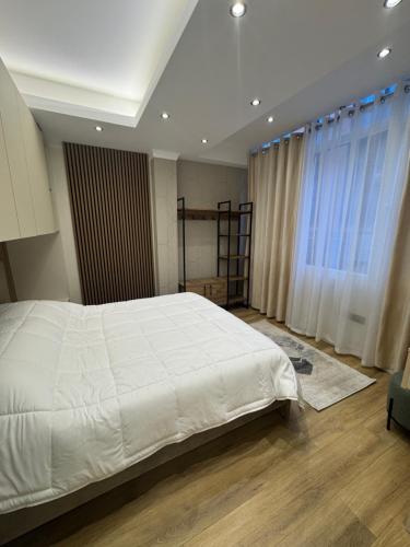 a bedroom with a large white bed and a window at Luxury Apartments Lezha in Lezhë