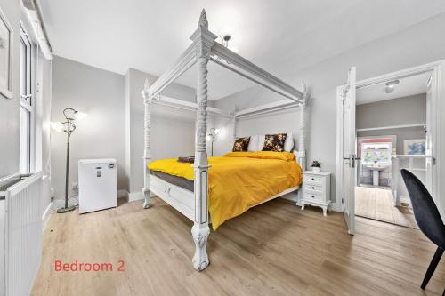 a bedroom with a white canopy bed with yellow sheets at Tranquil 2 Bedroom Rose Cottage near Stratford in London