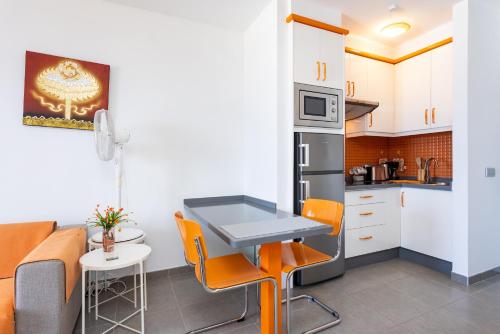 eine kleine Küche mit einem Tisch und orangefarbenen Stühlen in der Unterkunft Home2Book Relaxing Coastal Studio in Adeje in Adeje
