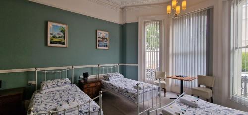 a bedroom with two beds and green walls at Westward Ho Hotel in Folkestone