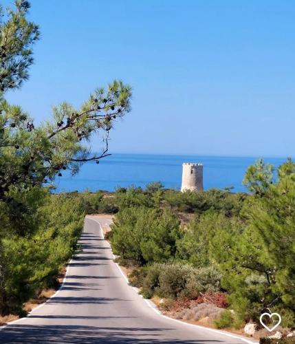 a road with a lighthouse in the distance at Vigliata Sidirounta Traditional Stonehouse in Chios