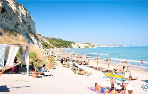 a group of people sitting on a beach with umbrellas at M&V House in Balchik