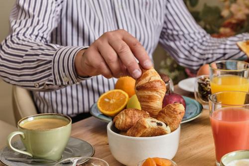 a man standing at a table with a bowl of pastries at Hotel Etoile Saint Ferdinand by Happyculture in Paris