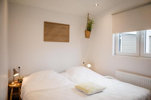 a white bedroom with a bed and a window at Mooi Chalet met sauna in hartje Zeeland VP080 in Heinkensand