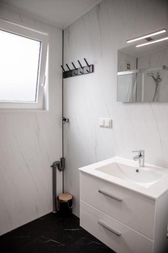 a white bathroom with a sink and a window at Mooi Chalet met sauna in hartje Zeeland VP080 in Heinkensand