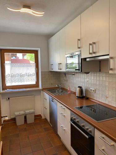 a kitchen with white cabinets and a sink and a window at Traumferienwohnungen Schliersee in Schliersee