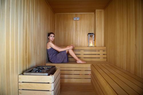 a woman is sitting in a sauna at Mirage Beach Spa Hotel in Eforie Nord