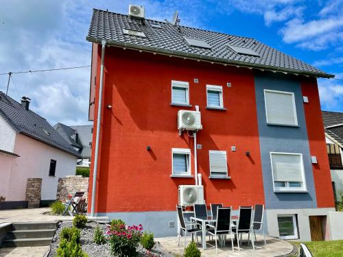 a red building with chairs in front of it at Haus Lotusblüte in Kelberg