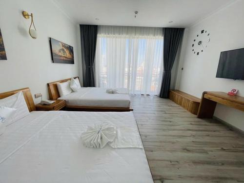 a hotel room with two beds and a television at HOLIDAY HOTEL PHAN THiẾT in Ấp Bình Hưng