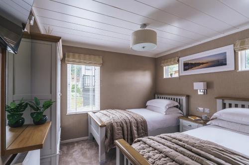 Un dormitorio con dos camas y una ventana. en Jennywren Lodge, en Windermere