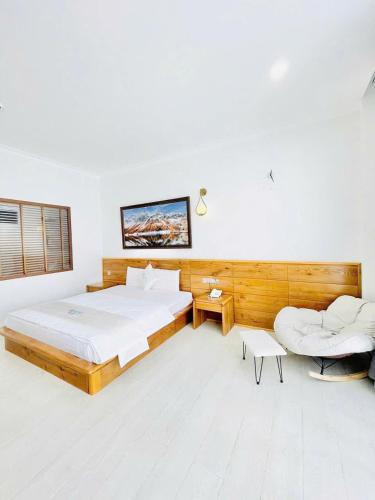 a bedroom with a large bed and a chair at HOLIDAY HOTEL PHAN THiẾT in Ấp Bình Hưng