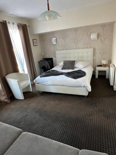 a bedroom with a white bed and a couch at Hôtel Le Square in Aurillac