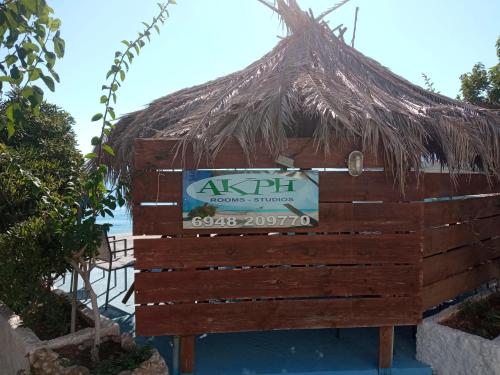 a straw hut with a sign in front of the ocean at Akri Rooms in Akrata